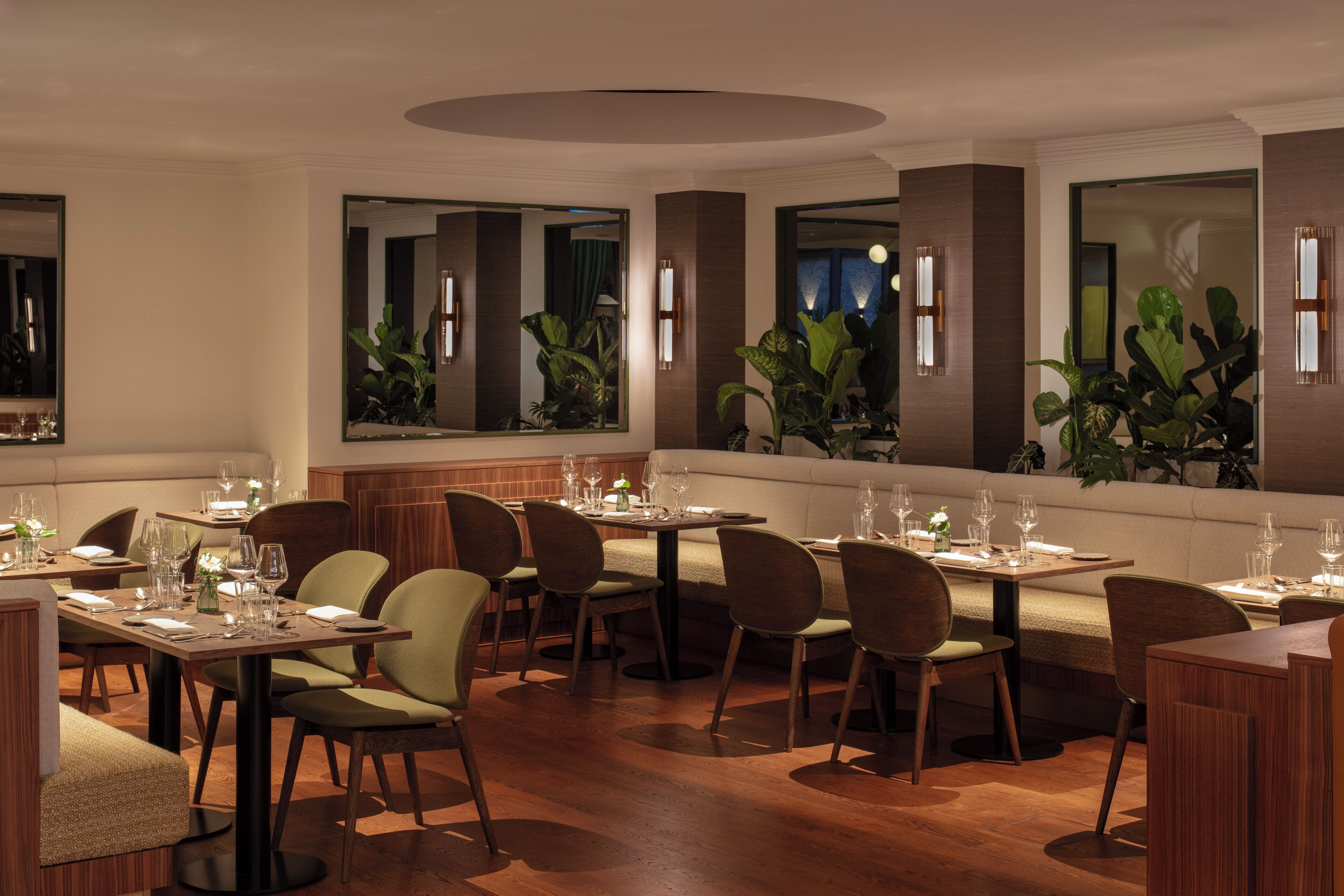 Un restaurant doté de nombreuses tables, de chaises et d’une grande variété de plantes.