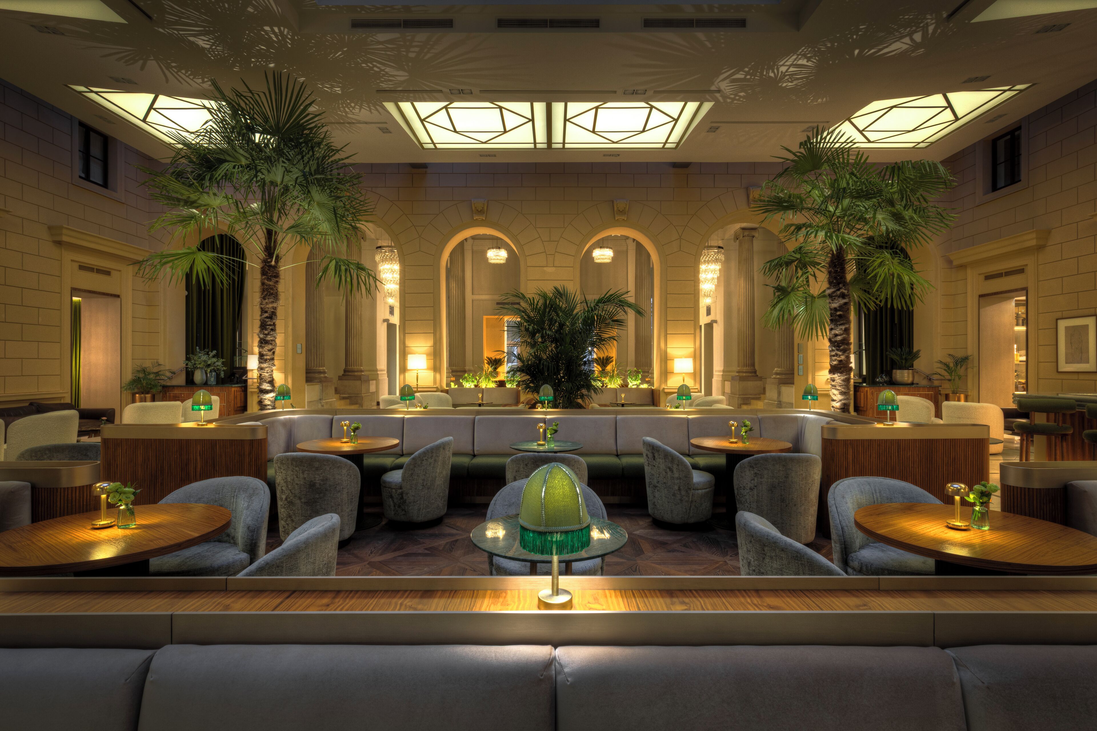 A lobby with seating areas, a reception desk, and a large mirror reflecting the space.