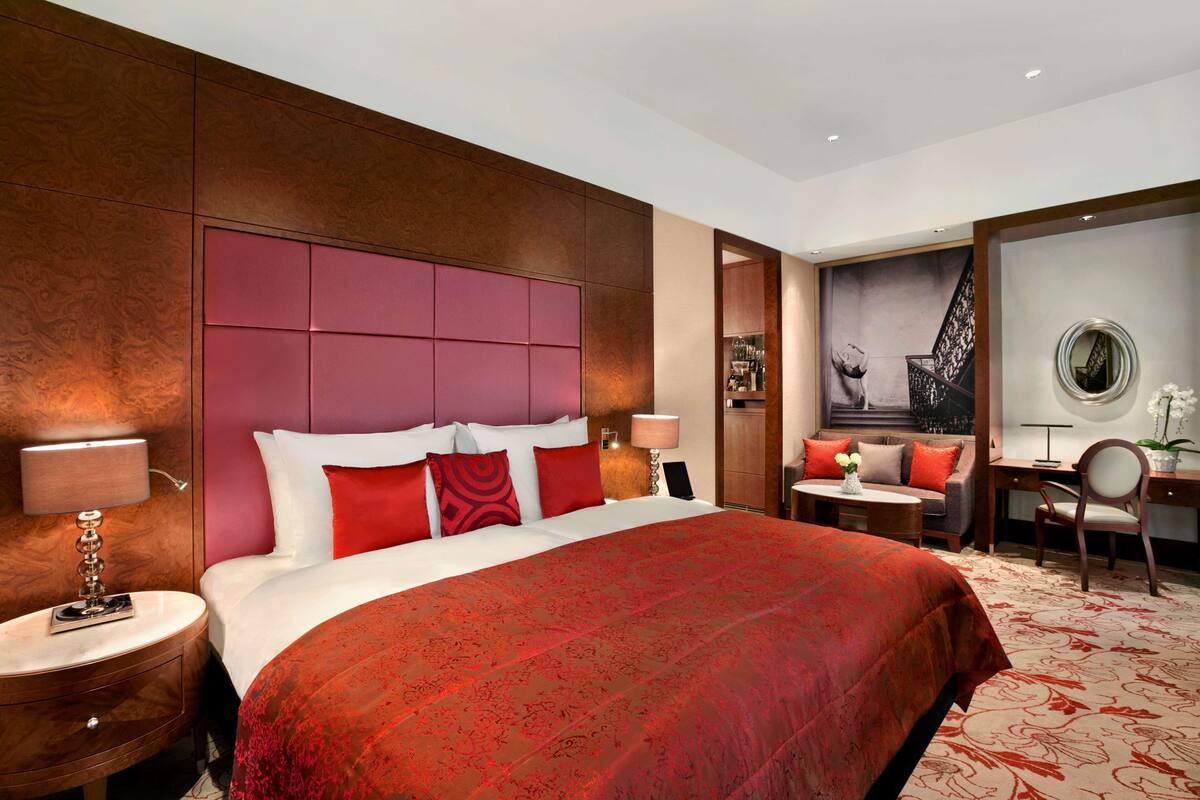 Ein Hotelzimmer mit einem großen Bett, einem Schreibtisch, einem Stuhl und Blick auf ein Gebäude.