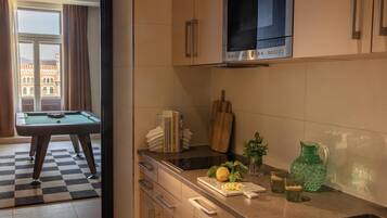 Una cocina moderna con mesa de billar, microondas y vista a un edificio a través del ventanal.