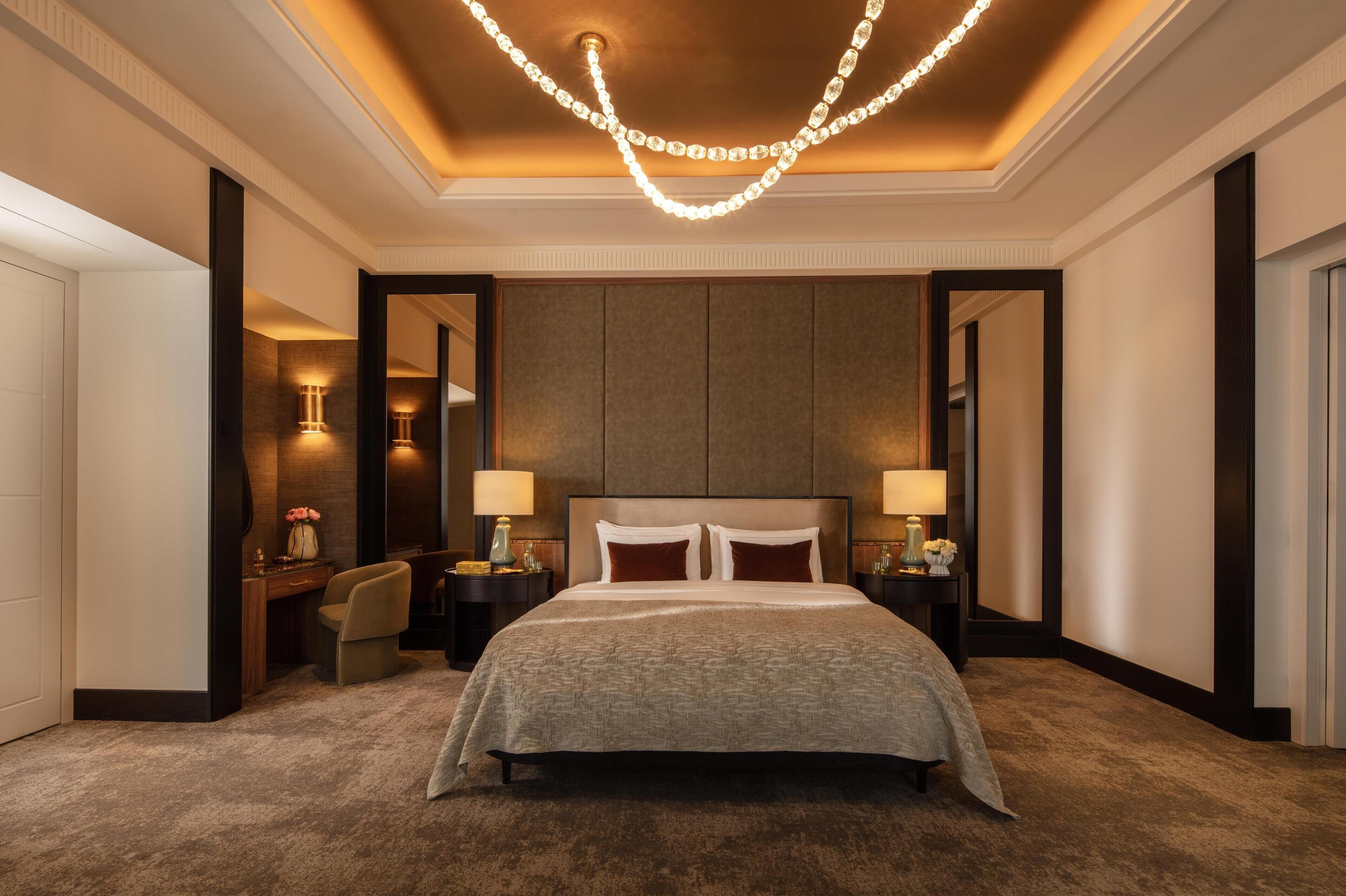 Amplia habitación de hotel con una cama grande, dos mesitas de noche con lámparas, un escritorio y una silla.