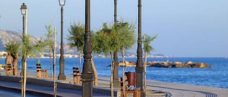 A seaside promenade with benches, street lamps, and a view of the sea.