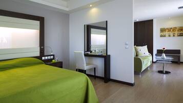 Una habitación de hotel con cama, escritorio, silla y una pequeña mesa redonda con un florero.