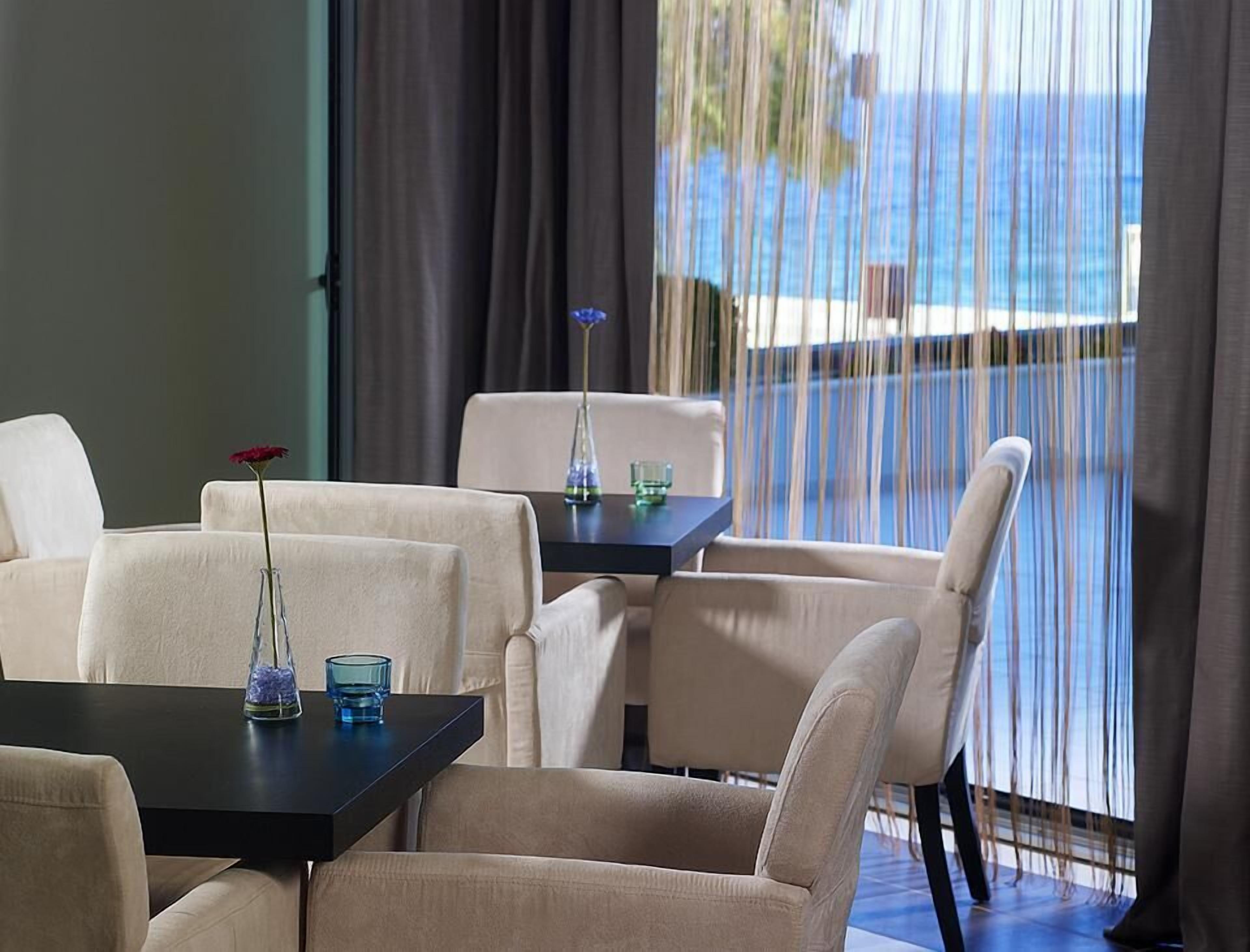 Une chambre avec vue sur la mer, comprenant une table avec des chaises et un vase avec une fleur.