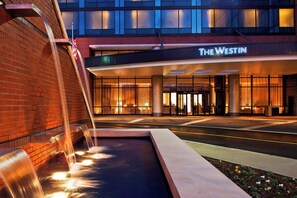 A hotel entrance with a water feature and an American flag.