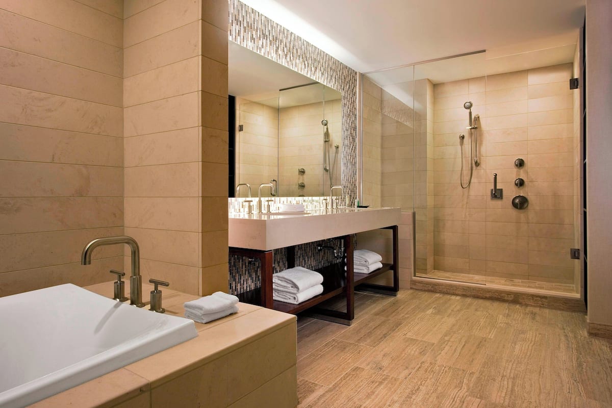 Un baño moderno con una bañera grande, una ducha con cerramiento de vidrio y un tocador con espejo.