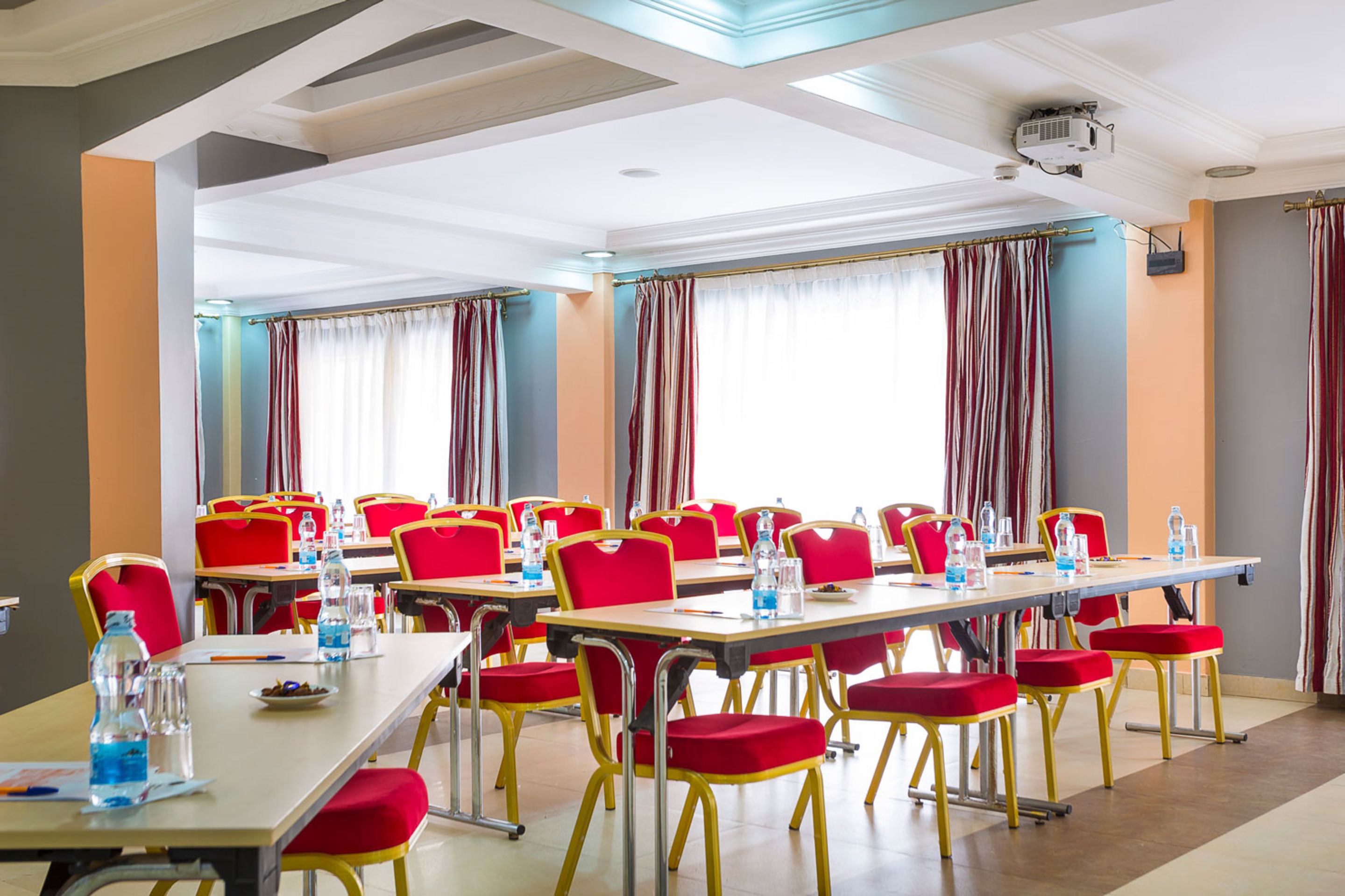 Un salón de conferencias con sillas, mesas y un proyector, todo en color rojo.