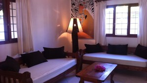 Una habitación con un sofá, una mesa con flores y un mural de cebra en la pared.
