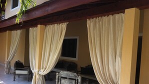 Un espacio de estar al aire libre cubierto, con un banco de madera y un televisor.