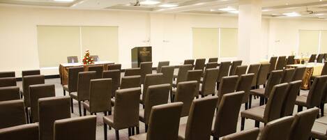 Un salón de conferencias con filas de sillas, un atril y un árbol de Navidad.