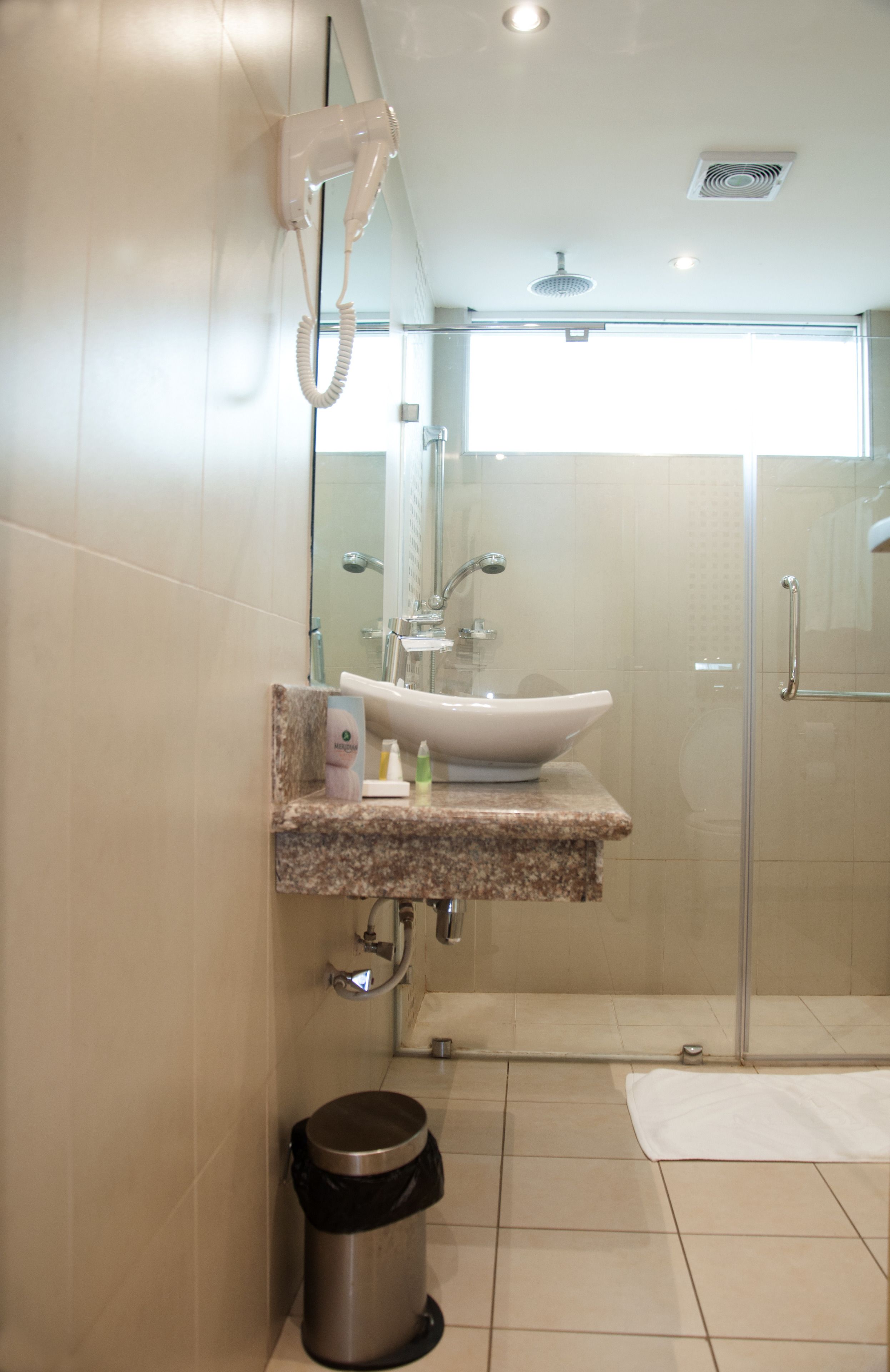 Un baño moderno con lavamanos, espejo e inodoro con ducha.
