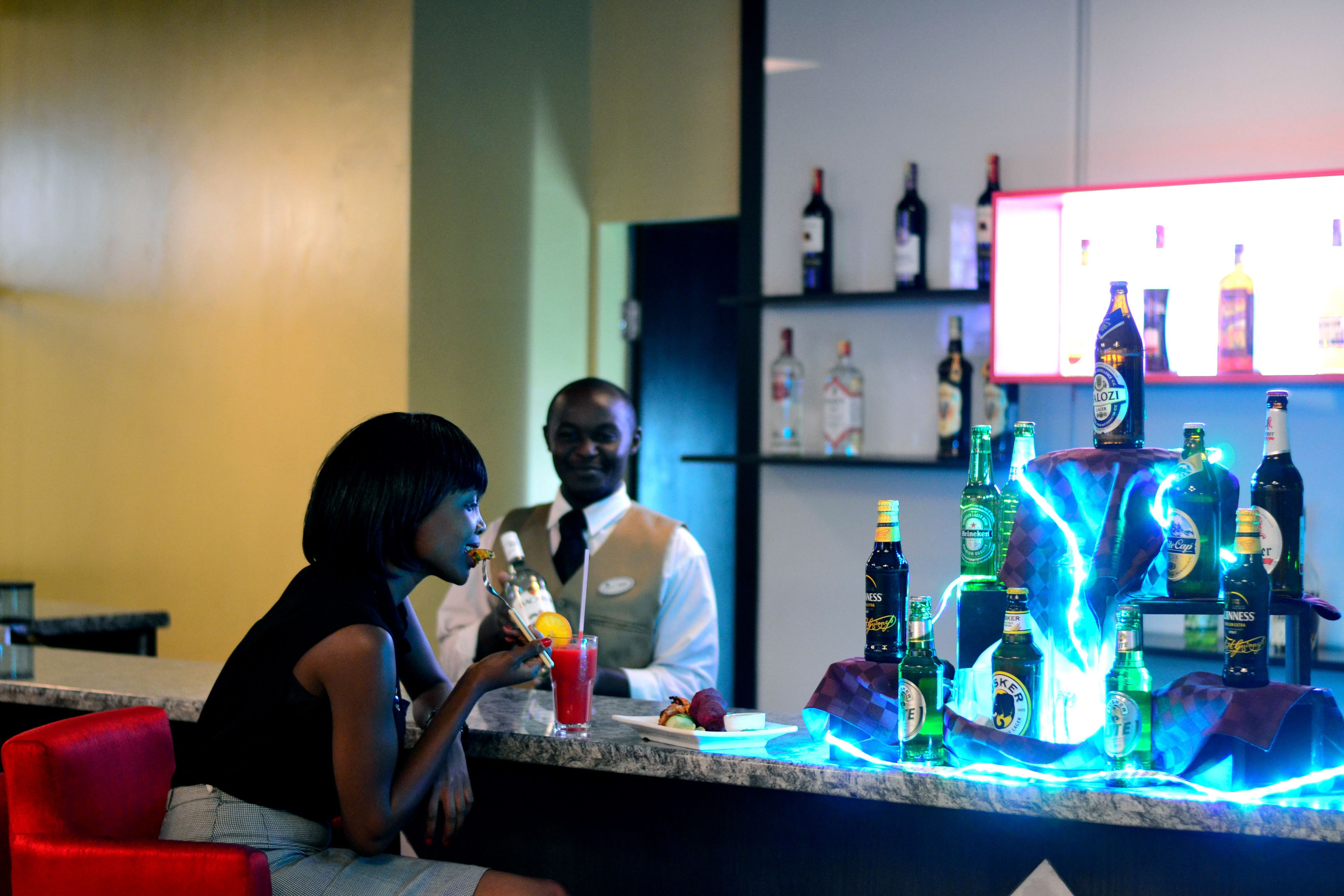A bar area with a counter, various bottles, and a person seated.