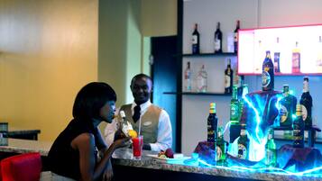 A bar area with a counter, various bottles, and a person seated.