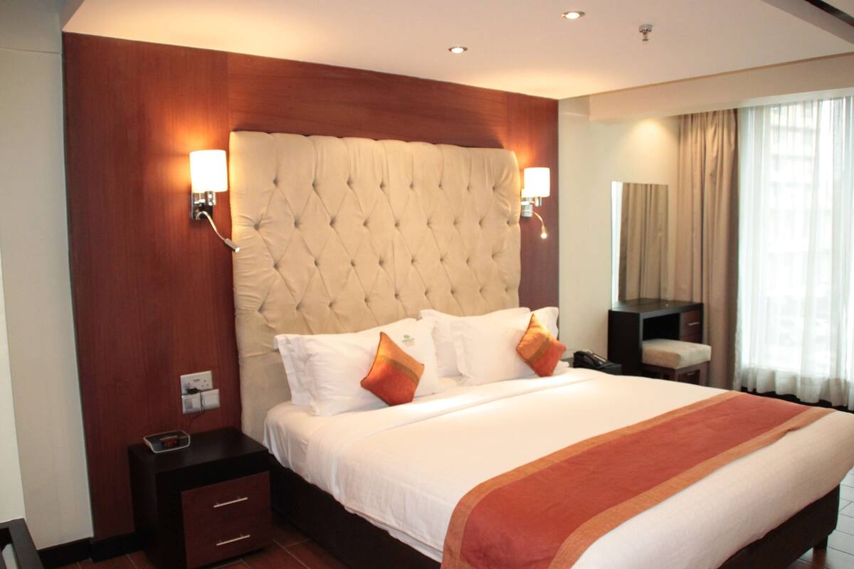 Une chambre d’hôtel avec un grand lit, deux lampes de chevet, une table de chevet et un miroir.