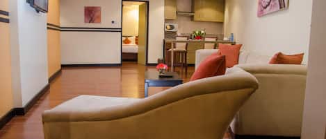 A living room with a sofa, a chaise lounge, and a dining area with a table and chairs.