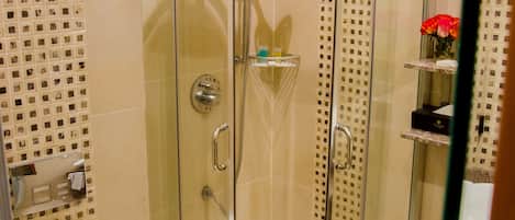 A bathroom with a glass-enclosed shower, a toilet, and a towel rack.