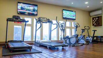Un gimnasio con cintas de correr, elípticas y bicicletas estáticas.