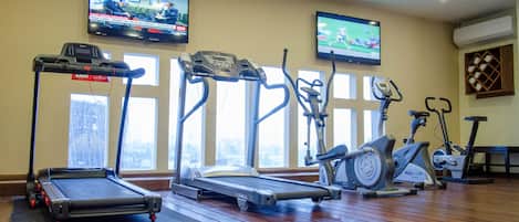 Un gimnasio con cintas de correr, elípticas y bicicletas estáticas.
