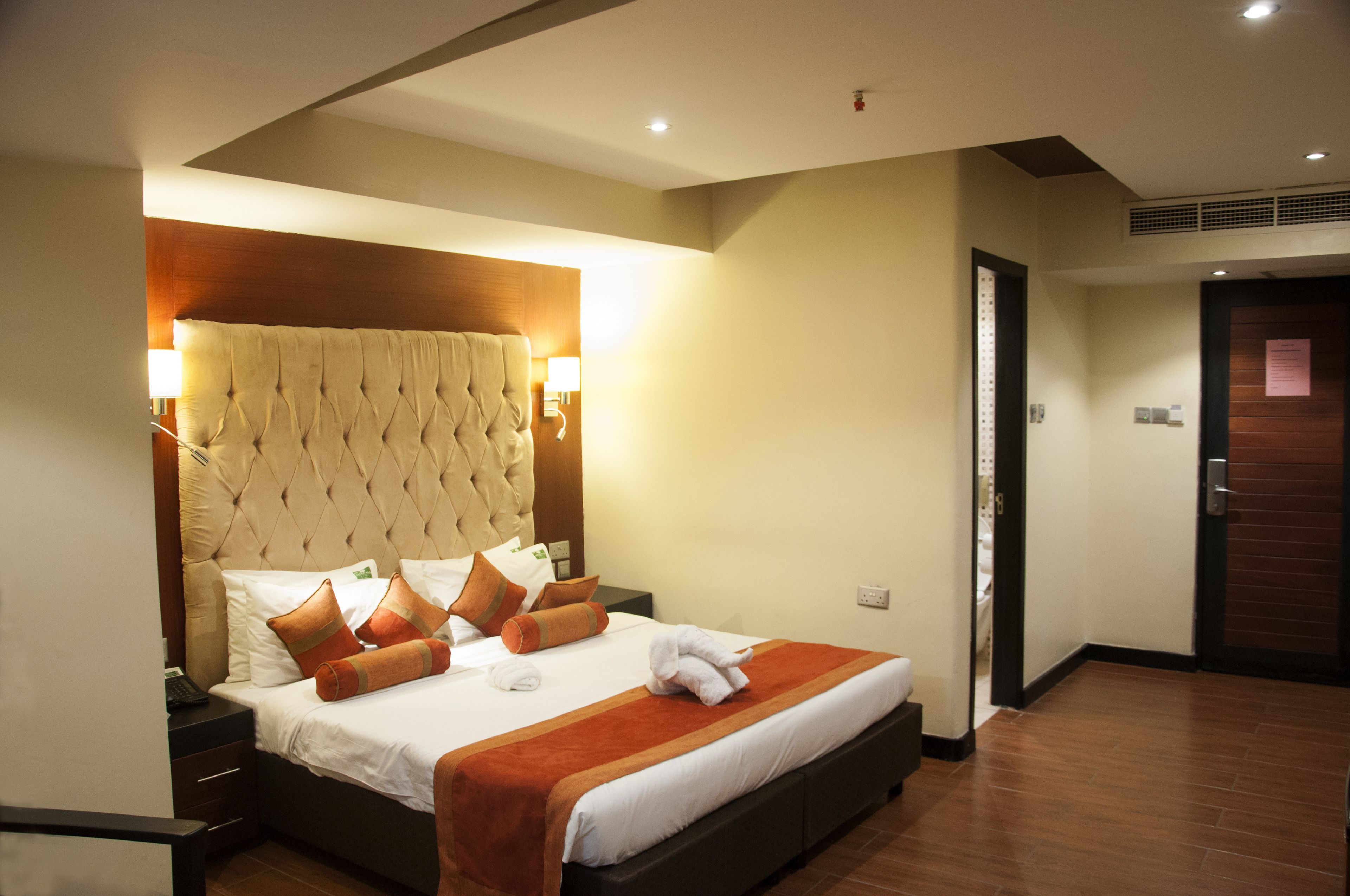 Une chambre d’hôtel avec un grand lit, une tête de lit en bois et une table de chevet.