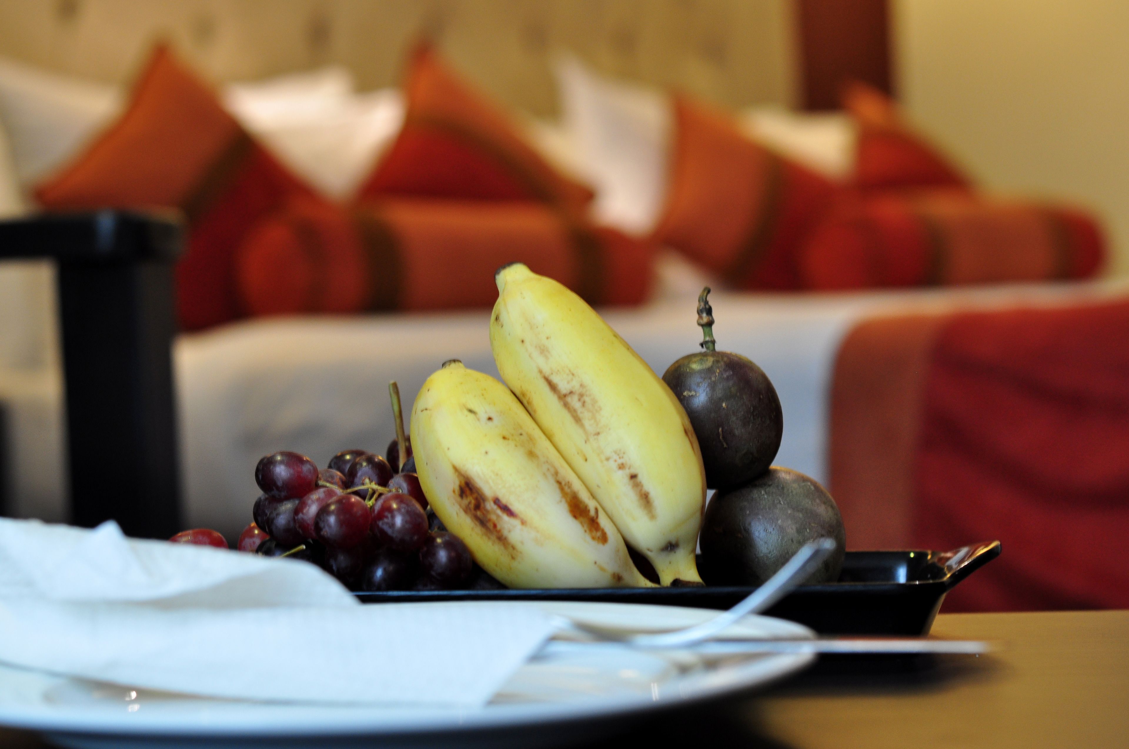 A dining table with a plate of fruit, including bananas and grapes, and a small bowl.