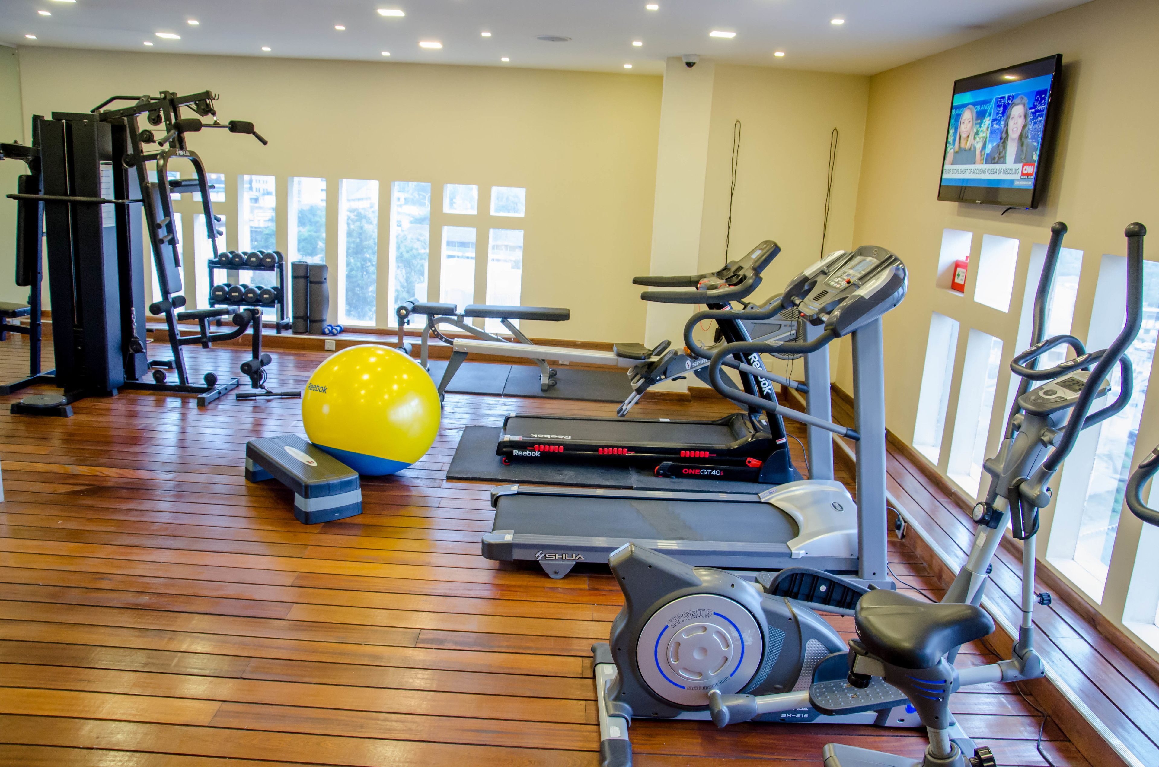 A gym with treadmills, elliptical machines, and a yellow exercise ball.
