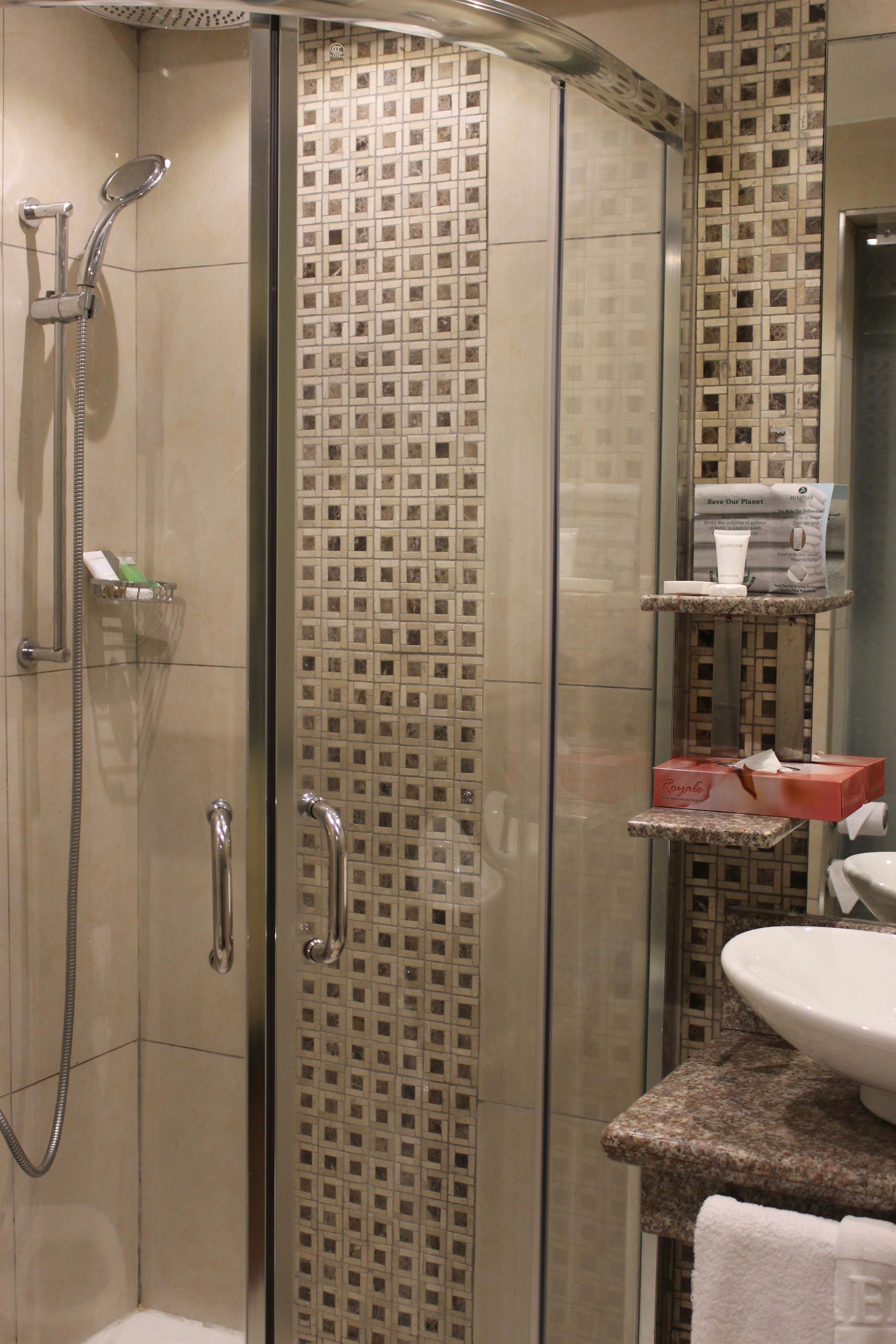 Un baño moderno con ducha de vidrio, un lavamanos y un espejo.