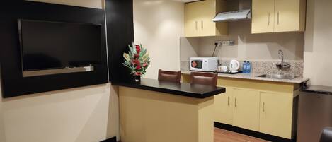 A compact kitchen with a microwave, sink, and a small refrigerator.