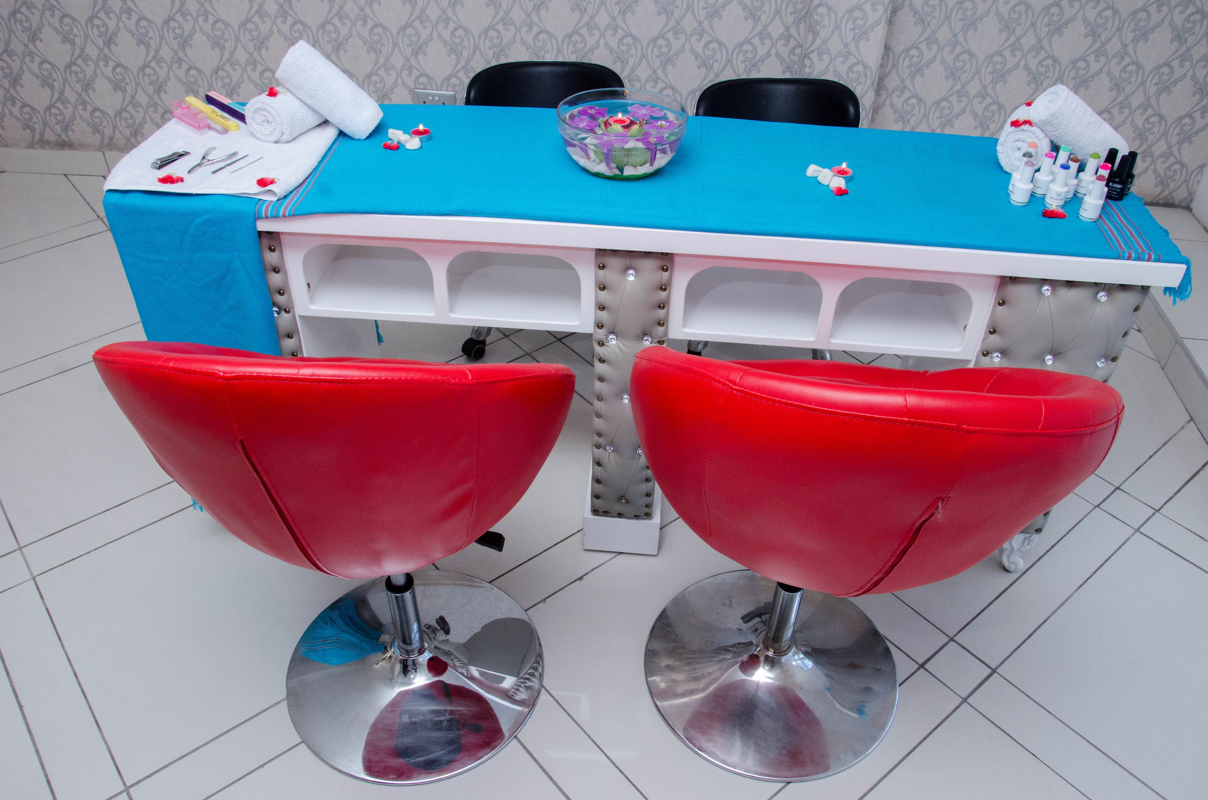 A salon with a blue table, red chairs, and various hairdressing tools.