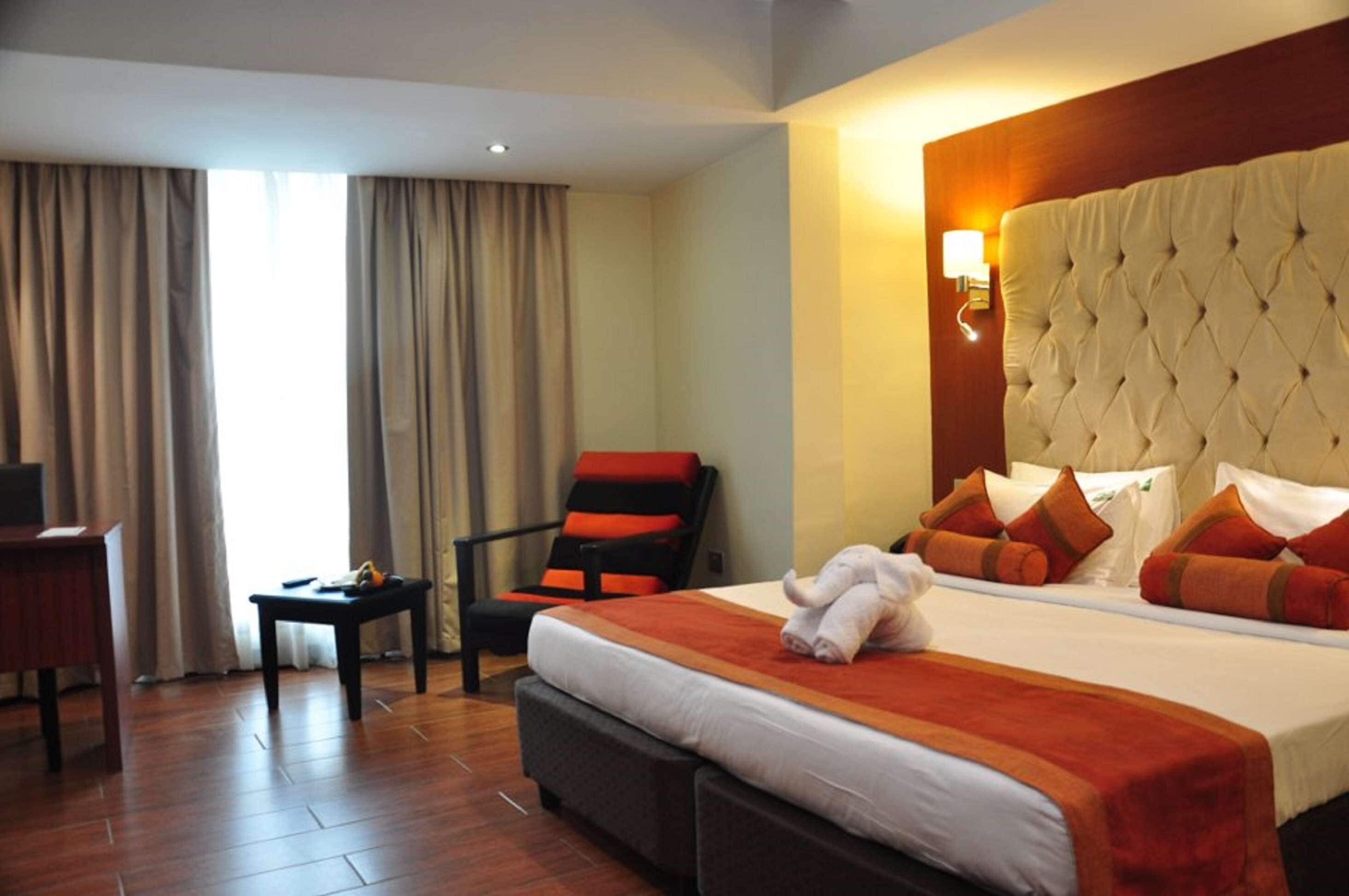 Una habitación de hotel con una cama grande, una silla, una mesita y un escritorio.