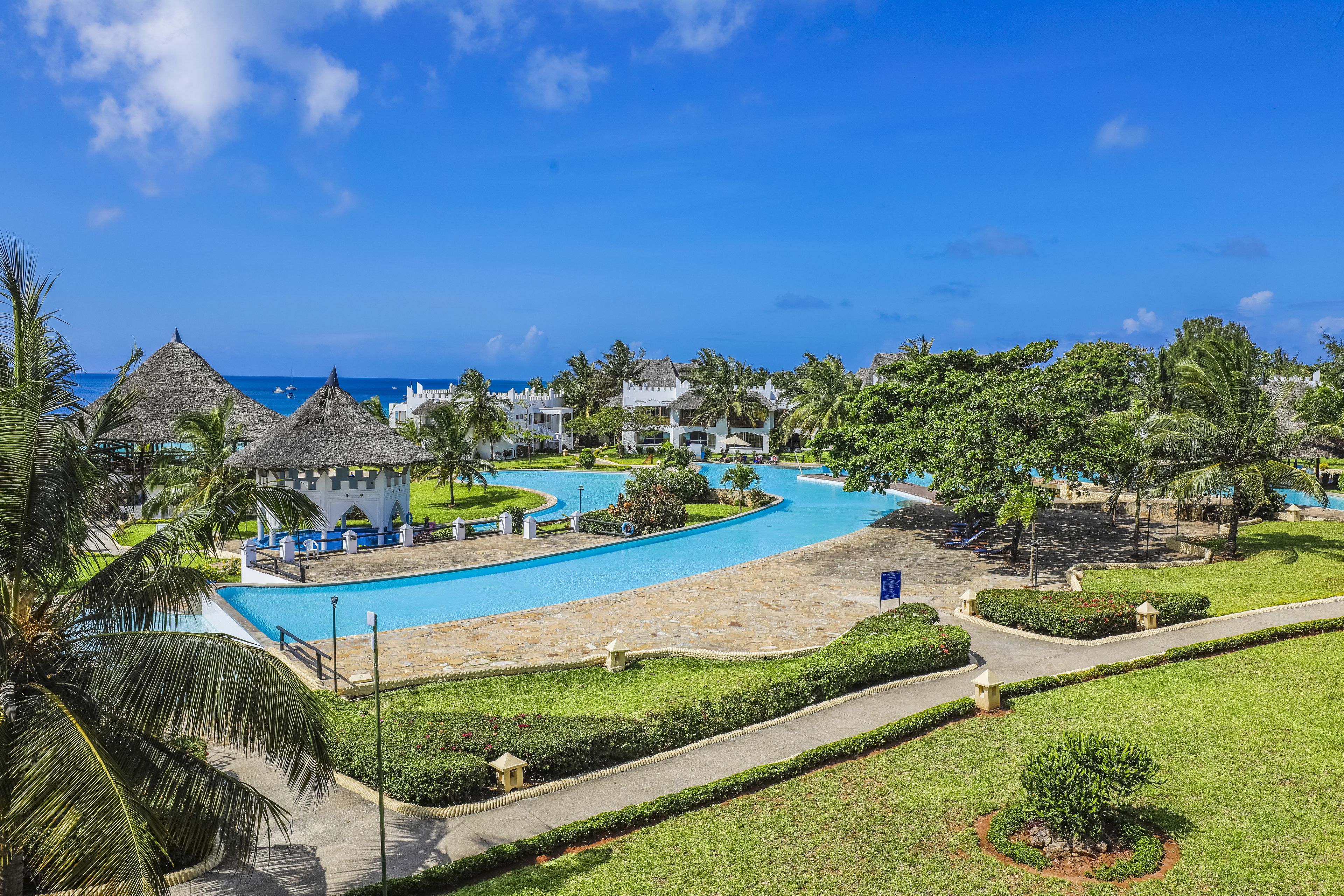 A resort with a swimming pool, palm trees, and beach views.