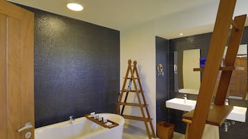 A modern bathroom with a bathtub, two sinks, a wooden ladder, and a large mirror.