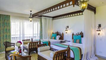 Una habitación de hotel con cuatro camas, muebles de madera y un candelabro.