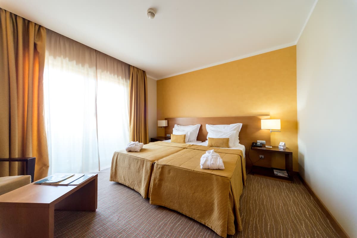 A hotel room with a large bed, a bedside table, a lamp, and a chair.