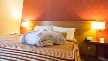 Ein Hotelzimmer mit einem ordentlich bezogenen Bett, zwei Nachttischlampen und einer roten Akzentwand.