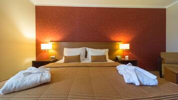 A hotel room with a large bed, two bedside lamps, and a brown striped bedspread.