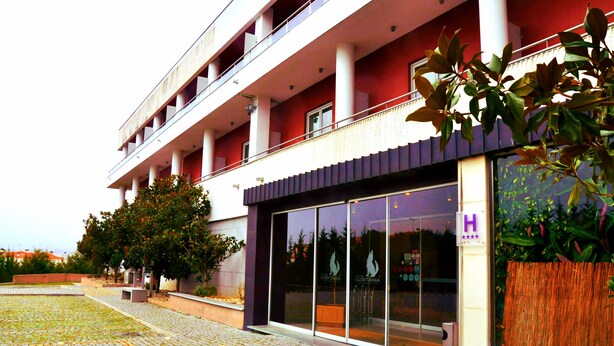 Een hotel met een moderne gevel, grote glasramen en een bord met een 4-sterren classificatie.