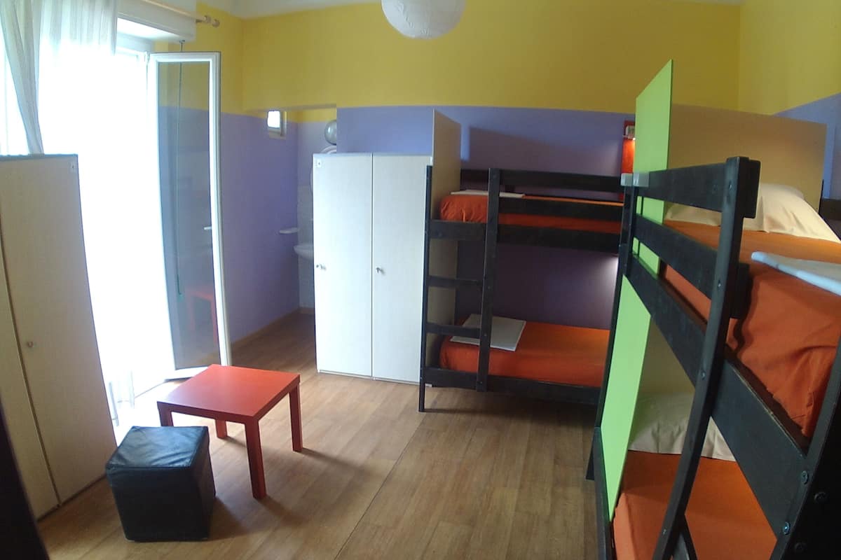 Ett studentrum med våningssängar, en garderob, ett bord och en liten pall.