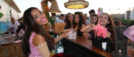 A bar area with a counter, a drink dispenser, and hanging lights.