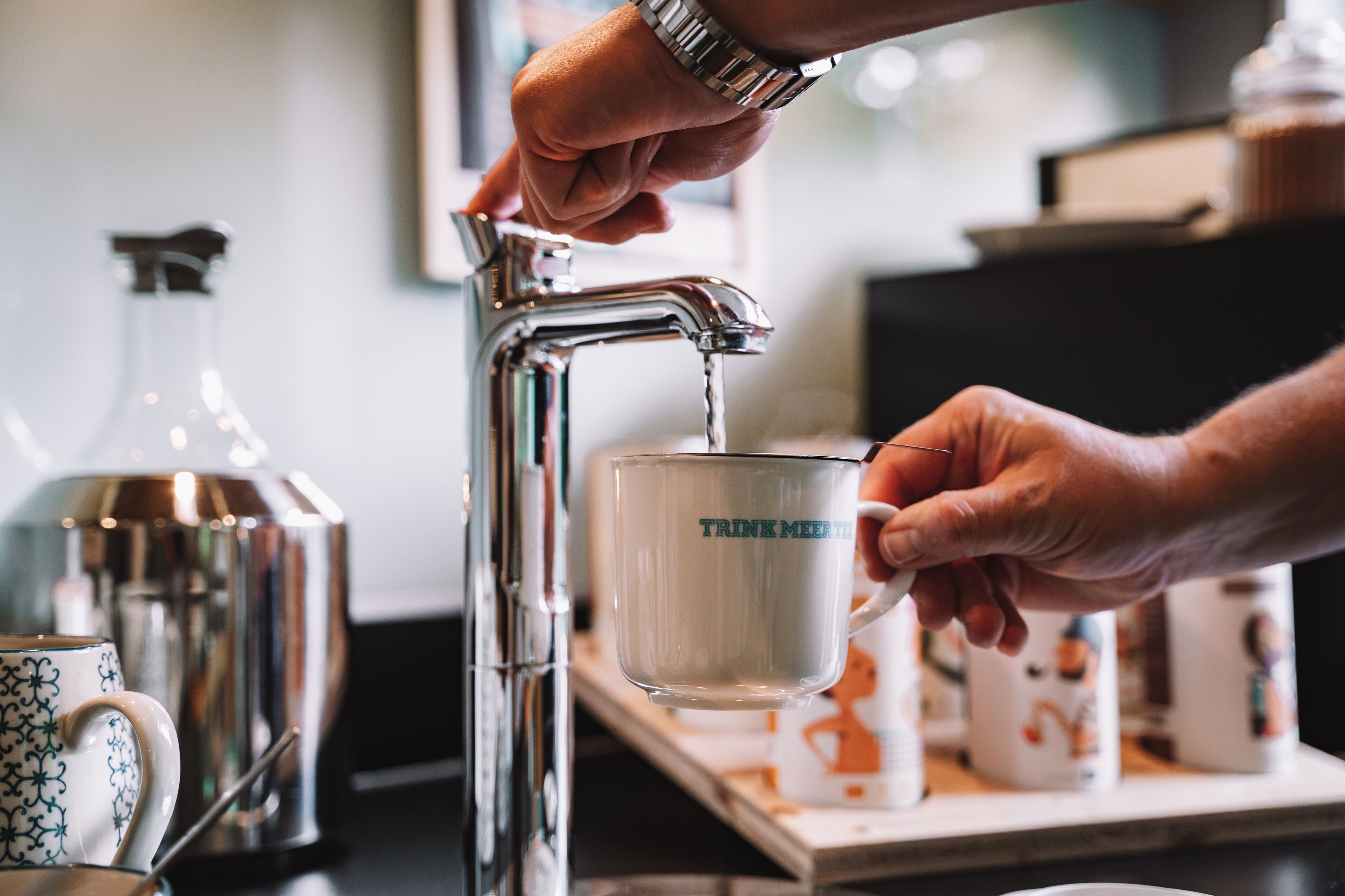 Une main qui remplit une tasse d’eau provenant d’un robinet.