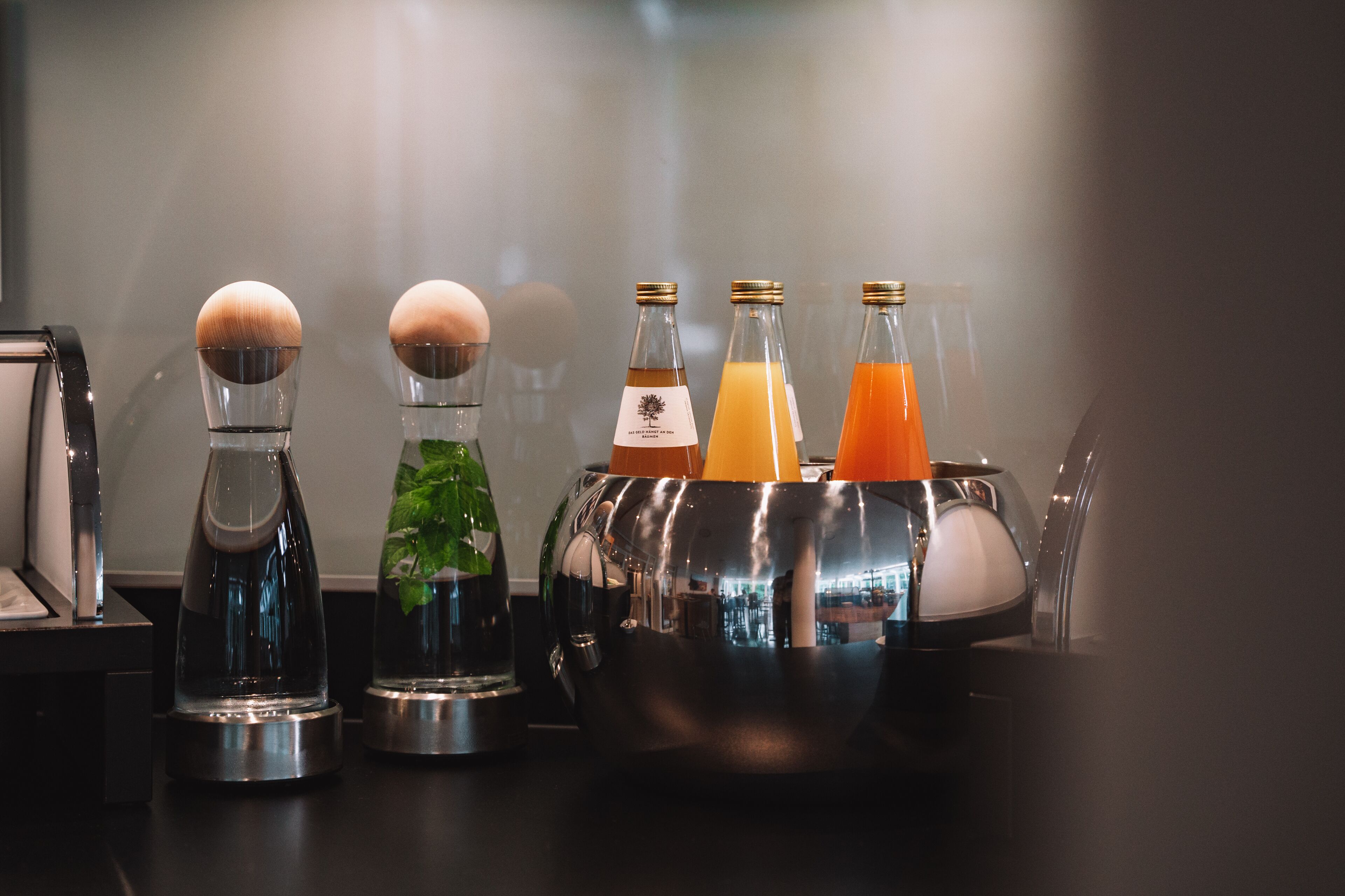 A bar area with various glassware and bottles, including a metal bucket with bottles of orange juice.