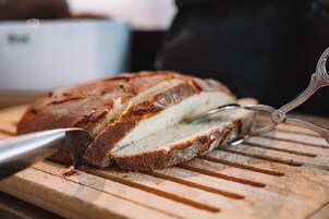 Una barra de pan siendo cortada sobre una tabla de madera.