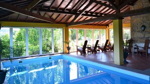 En indendørs swimmingpool med træloft og store vinduer.