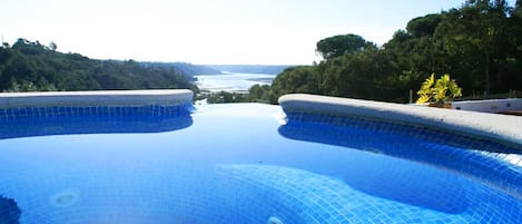 Una piscina al aire libre, sombrillas, sillones reclinables de piscina