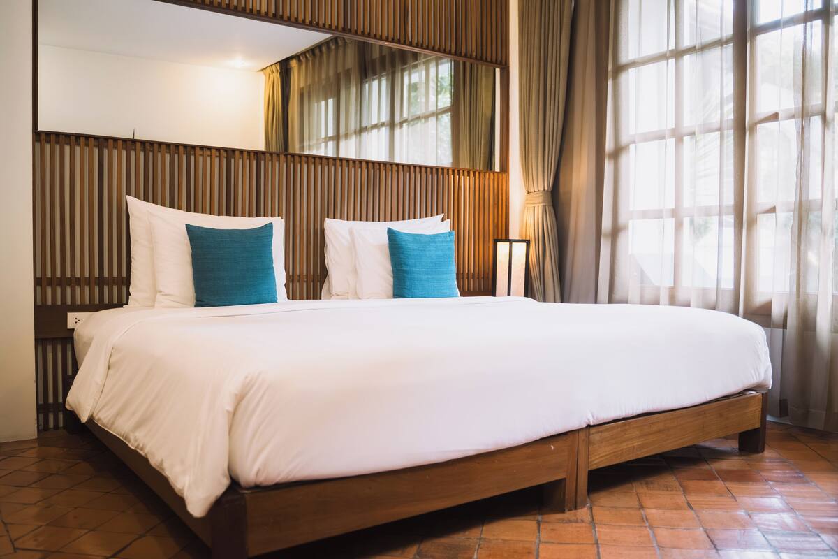 A large bed with a wooden frame, white bedding, and two blue pillows.