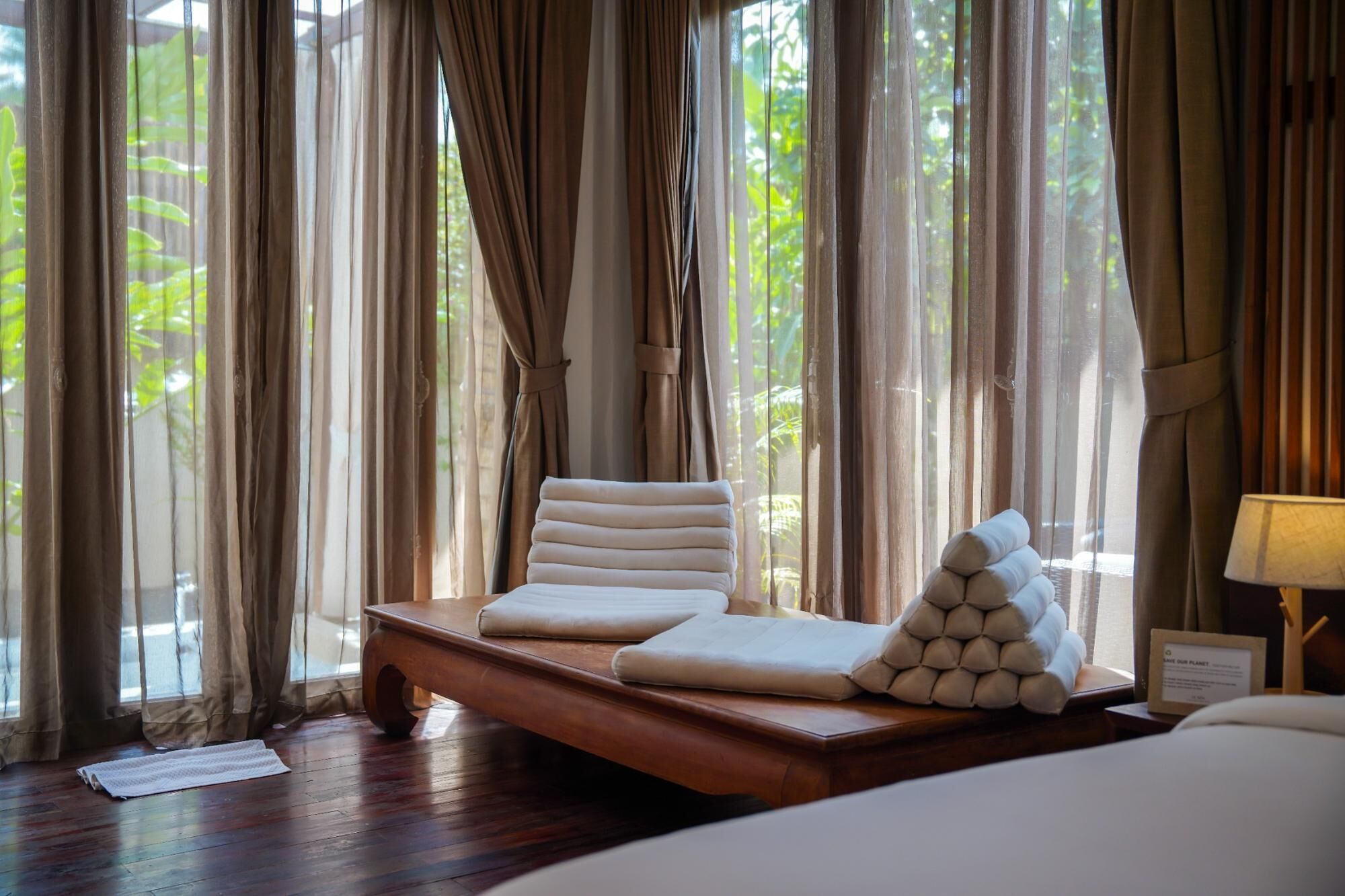 A room with a bed, a wooden table, and a lamp.
