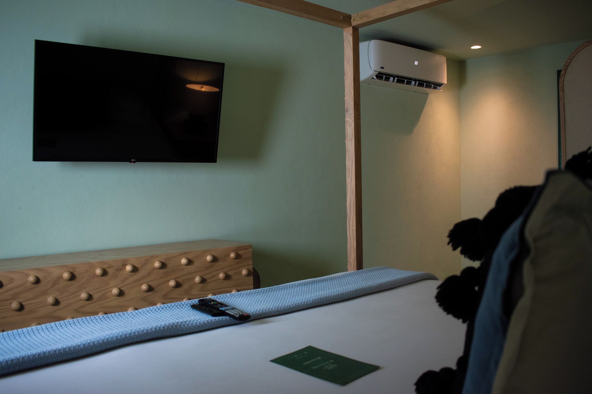 Una habitación con una cama, televisión instalada y aire acondicionado.