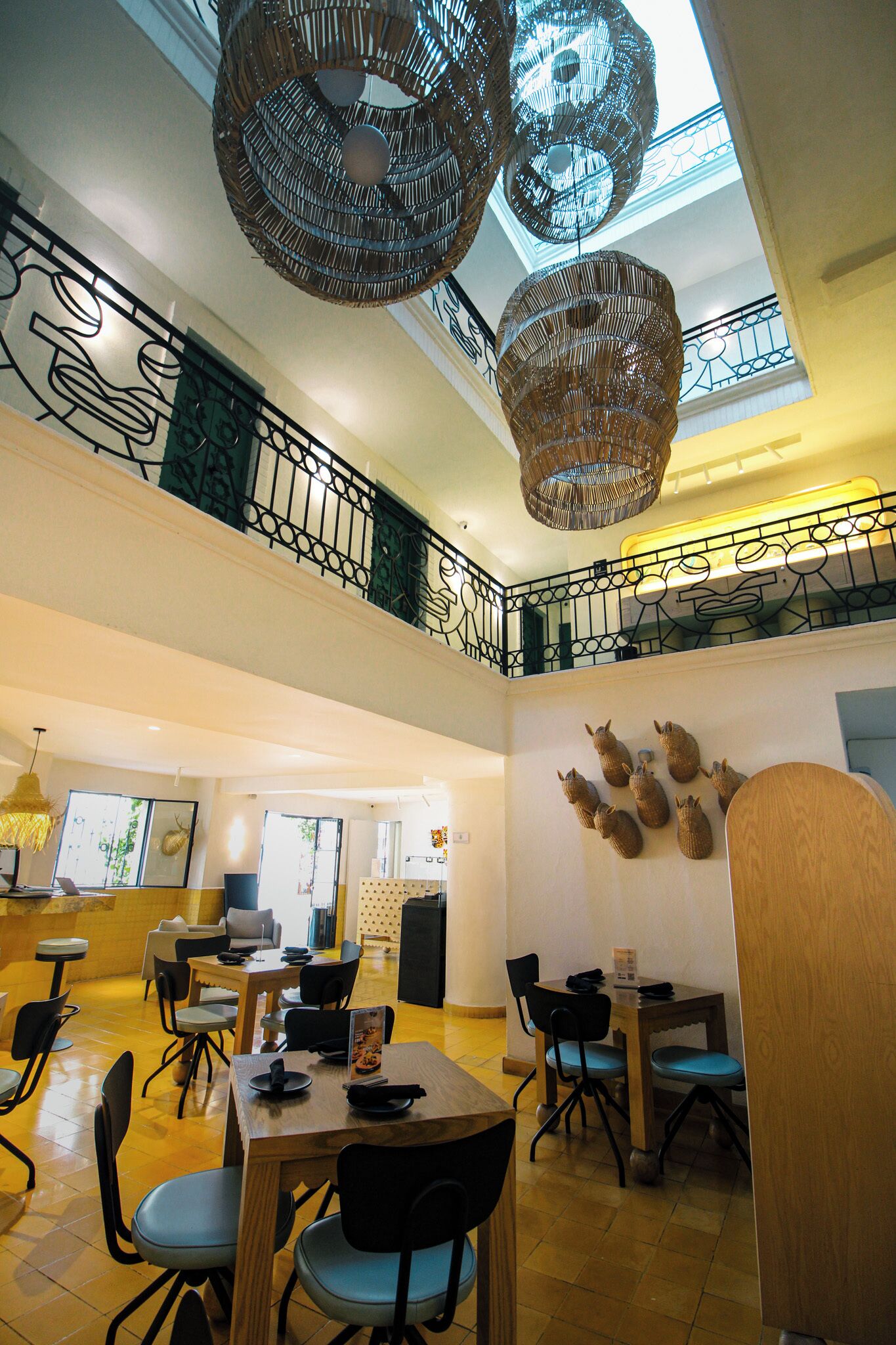 A spacious indoor area with a high ceiling, multiple dining tables and chairs, and decorative wall-mounted sheep.