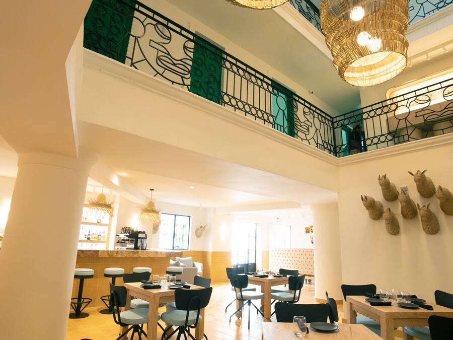 A dining area with high ceilings, chandeliers, and a view of the upper floor.