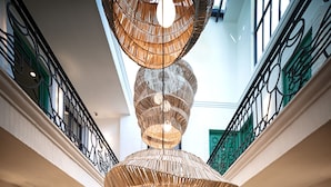 Un interior de varios niveles con una escalera caracol central, puertas verdes y un lámpara colgante decorativa.