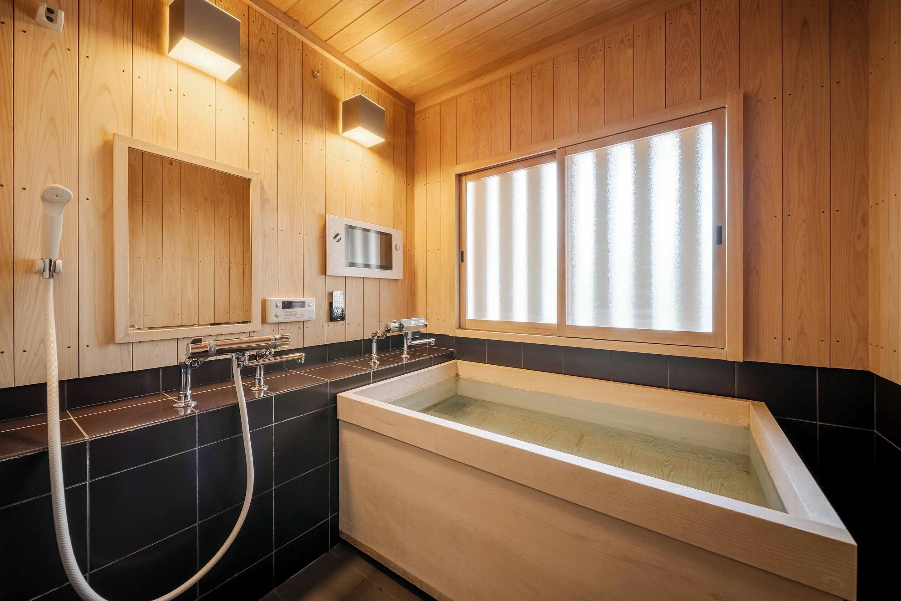 A wooden-paneled bathroom with a large bathtub, a shower area, and a microwave.